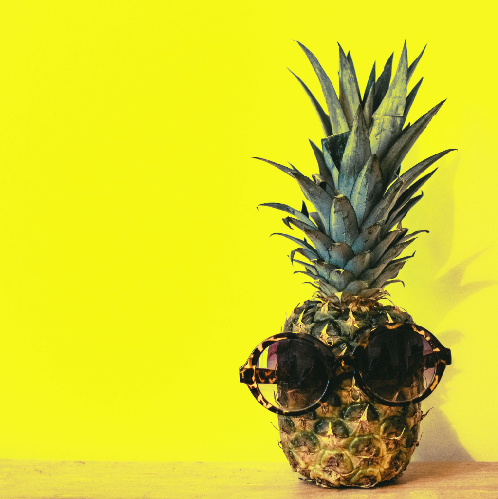 Un ananas portant des lunettes de soleil rondes foncées sur un fond jaune vif rappelle de manière fantaisiste la nécessité de faire une pause.