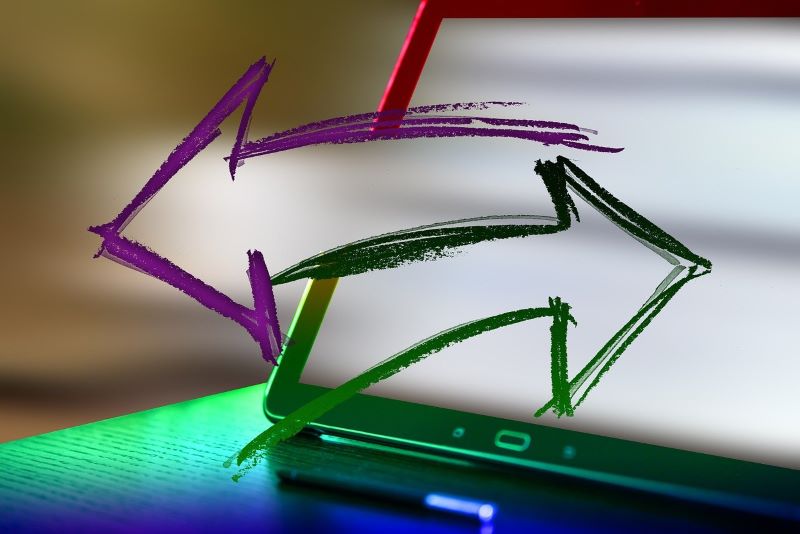 A tablet screen displaying two painted arrows, a purple one pointing to the left and a green one pointing to the right, with a blurred background, symbolizes the different directions for Vocational Training in 2024.