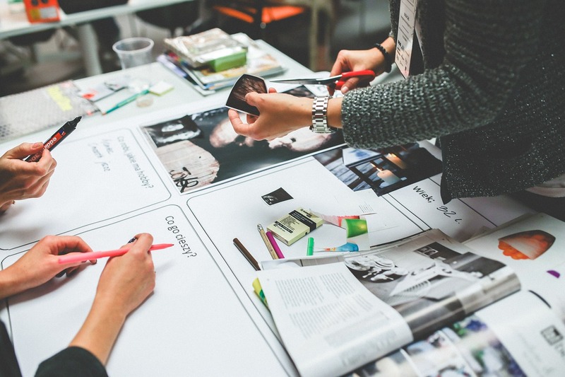 Des personnes travaillant en collaboration sur un projet avec des papiers, des stylos et un smartphone sur la table, favorisant un environnement qui privilégie la santé mentale en entreprise.